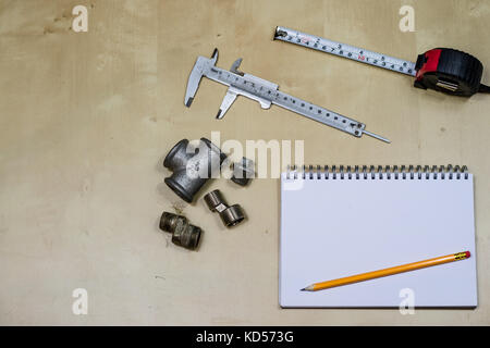 Materialien, Zubehör und Ersatzteile für Hydraulik. Noten- und Messwerkzeuge auf dem Workshop Tabelle. Holztisch. Stockfoto