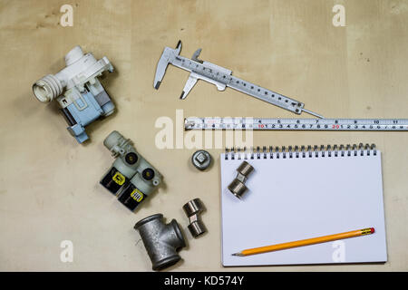 Materialien, Zubehör und Ersatzteile für Hydraulik. Noten- und Messwerkzeuge auf dem Workshop Tabelle. Holztisch. Stockfoto