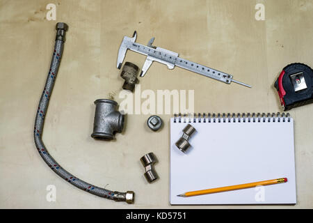 Materialien, Zubehör und Ersatzteile für Hydraulik. Noten- und Messwerkzeuge auf dem Workshop Tabelle. Holztisch. Stockfoto