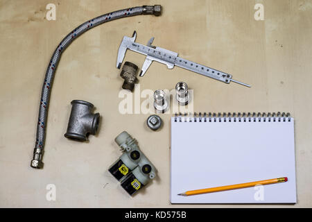 Materialien, Zubehör und Ersatzteile für Hydraulik. Noten- und Messwerkzeuge auf dem Workshop Tabelle. Holztisch. Stockfoto