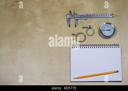 Materialien, Zubehör und Ersatzteile für Hydraulik. Noten- und Messwerkzeuge auf dem Workshop Tabelle. Holztisch. Stockfoto