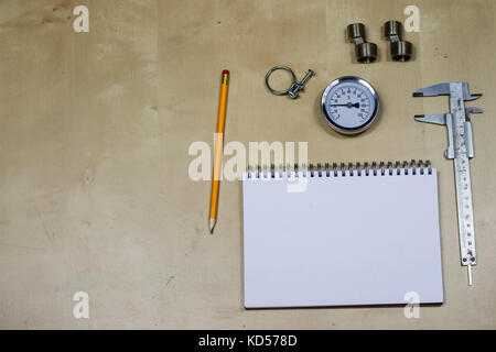 Materialien, Zubehör und Ersatzteile für Hydraulik. Noten- und Messwerkzeuge auf dem Workshop Tabelle. Holztisch. Stockfoto