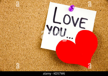 Eine gelbe Haftnotiz schreiben, caption, Beschriftung Phrase liebe dich... in Schwarz ext auf einem weißen Haftnotiz zu einem Kork Pinnwand angeheftet Stockfoto