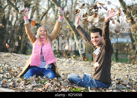 Teenager Jungen und Mädchen spielen in den Blättern und freuen uns auf Herbst und Freundschaft Stockfoto