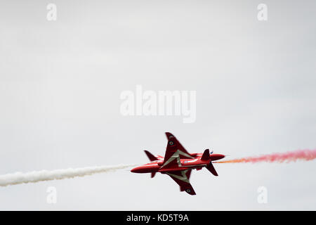 Zwei Flugzeuge des Royal Air Force Aerobatic Team (Red Arrows) passieren einander in Nahweite oberhalb des Militärflugplatzes in Leeuwarden. Stockfoto