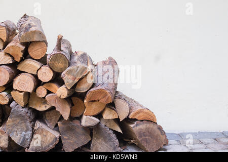 Feuerholz Stapeln auf dem Boden vor einer weißen Wand, einen Holzschuppen, Herbst Winter Hintergrund, Schneiden Baumstämme Stockfoto