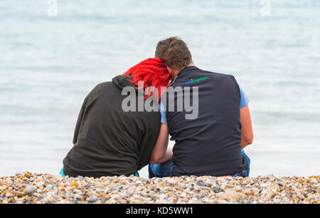 Junges Paar sitzt auf einem Strand am Meer in einem Moment. Stockfoto