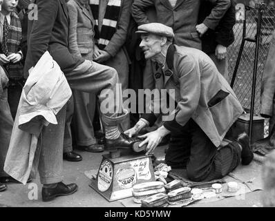 Deaktiviert Schuhputzmaschine/-Mann mit nur einem Bein polieren school Jungen Schuhe auf in London 1954 Schuhputzmaschine/-mann. Stockfoto