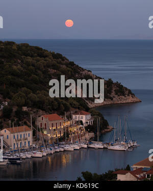 Ein Harvest Moon steigt über das Ionische Meer am Eingang zu dem kleinen Hafen von Kioni auf der Insel Ithaka in Nordgriechenland Stockfoto
