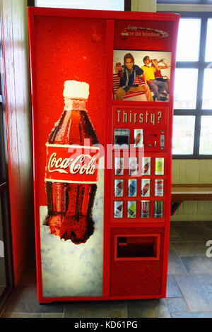 Ein Mann Geld in einem roten coca cola Maschine in einer Ruhezone. Stockfoto