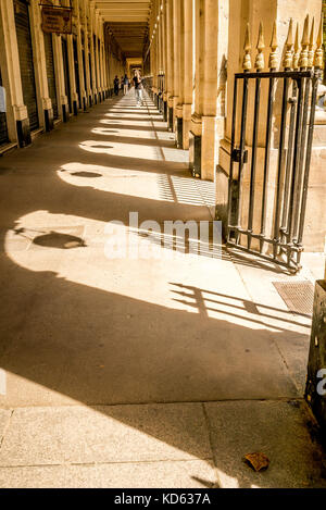 Eine Frau läuft durch die überdachten Arkaden im Palais Royal in Paris, Frankreich Stockfoto