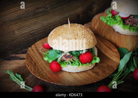 Hausgemachte Burger mit Rindfleisch, Radieschen, Salat, auf hölzernen Hintergrund serviert. Stockfoto