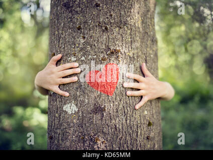 Baum umarmt, kleiner Junge gibt einem Baum eine Umarmung mit rotem Herz Konzept für die Liebe Natur Stockfoto