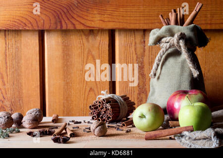 Frische reife rote Äpfel und Zimtstangen auf Holz- Hintergrund. Stockfoto