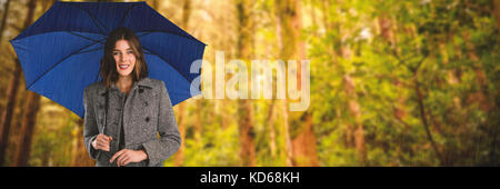 Porträt der jungen Frau mit Regenschirm gegen niedrigen Winkel Blick auf die Bäume Stockfoto