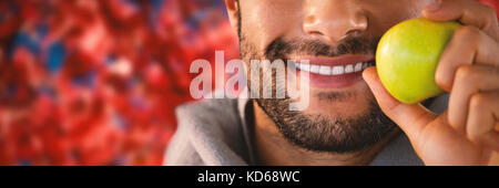 Close-up von lächelnden Mann hält Apple gegen Bäume im Herbst während der sonnigen Tag Stockfoto