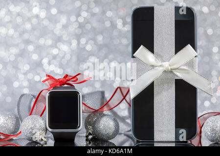 Smartphone und erobert und Dekorationen für den Weihnachtsbaum auf schwarzem Glas Tisch. Fokus auf dem Smartphone. Stockfoto