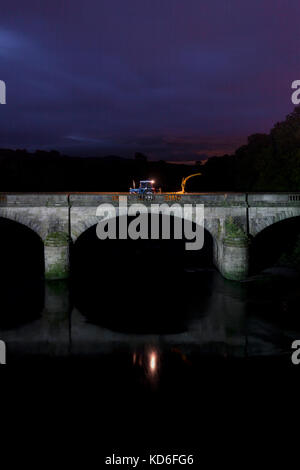 1988 Ford 7610, tritt zwei Traktor und New Holland 525 Feldhäcksler auf einer Brücke bei Nacht wiederhergestellt Stockfoto