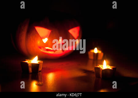 Scary Halloween Kürbis und Melone Jack-o-lanterns auf schwarzen Hintergrund mit kleinen, runden und Star Kerzen. selektive Fokus, Bokeh. Stockfoto