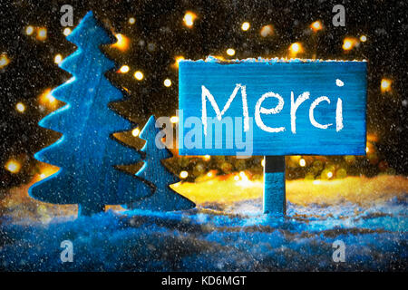 Schild mit französischen Text merci bedeutet Danke. blaue Weihnachtsbaum mit Schnee und Magic glühenden Lichter im Hintergrund und Schneeflocken. Karte für Jahreszeiten gree Stockfoto