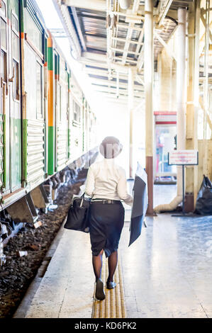 Eine Lady mit ihrem Schirm macht ihren Weg entlang der Plattform in Hua Lamphong Bahnhof Bangkok Thailand. Stockfoto