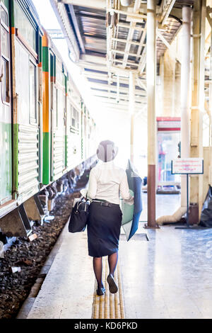 Eine Lady mit ihrem Schirm macht ihren Weg entlang der Plattform in Hua Lamphong Bahnhof Bangkok Thailand. Stockfoto