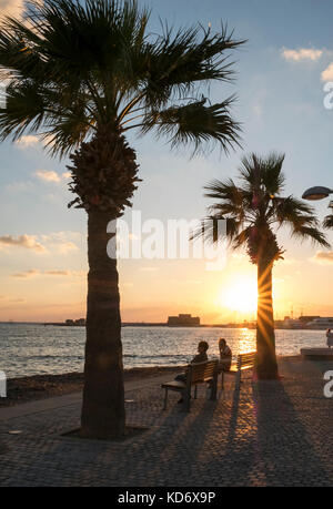 Touristen beobachten Sie den Sonnenuntergang an der Promenade in Kato Paphos, Paphos, Zypern Stockfoto