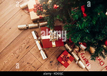 Weihnachten Hintergrund mit Dekorationen und Geschenkboxen auf Holzboden. Schön verpackt Weihnachten Geschenke und Knallbonbons platziert neben einem Chri Stockfoto