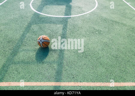 Alte Basketball auf einen Baskettballplatz draußen an einem sonnigen Tag links, Raum für Text oder Kopie Raum Stockfoto