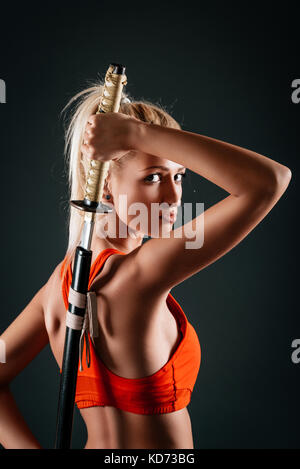 Süße Mädchen Zeichnung Katana hinter zurück und schaut in die Kamera. Stockfoto