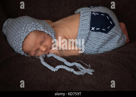 Neugeborenes Baby in einem grauen gestrickten Anzug schläft in einem schönen darstellen Stockfoto