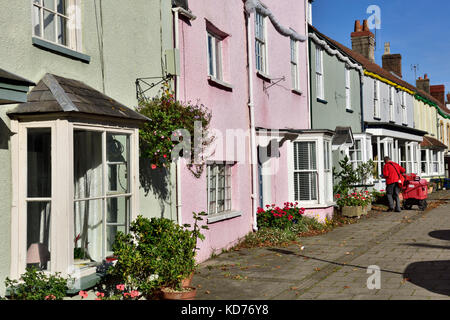 Postman die Lieferungen auf Umläufen in der Zeile von terrassenhäusern an der High Street in der kleinen englischen Stadt Thornbury, South Gloucestershire Stockfoto