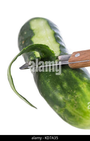 Gurke, die mit einer Holz- Schäler und Rinde von geschälten Gurke auf Weiß geschält Stockfoto