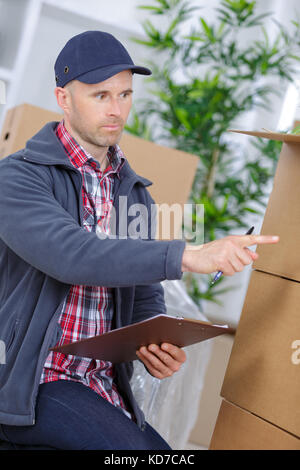 Fröhlicher junger Mann mover Halten eines Kartons Stockfoto