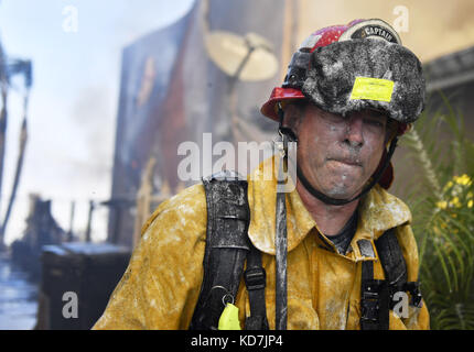 Anahiem Hills, Kalifornien, USA. Oktober 2017. Durchnässt Feuerwehrmann nach dousing ein Haus in Flammen, als der Canyon Feuer brennt in Anaheim Hills. Mindestens sechs Häuser brannten am frühen Nachmittag, als starke Santa Ana-Winde Evakuierungen in Orange County erzwangen. Kredit: Stuart Palley/ZUMA Wire/Alamy Live News Stockfoto