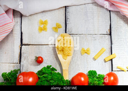 Lecker frischen bunten Zutaten zum Kochen Pasta Tagliatelle mit frischer Petersilie und Tomaten. Horizontale. holztisch Hintergrund. Stockfoto