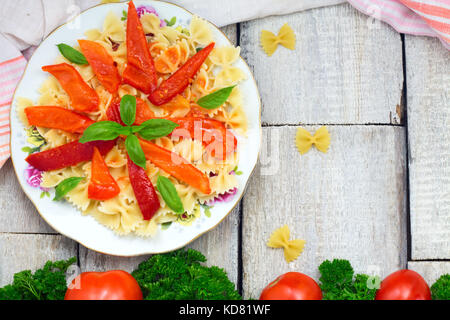 Farfalle Nudeln mit Tomaten, Paprika und Dasil auf rustikalen Holzmöbeln Hintergrund mit Kopie Raum Stockfoto