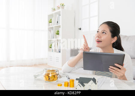 Gerne schöne Hausfrau über Mobile pad computer Tagträumen und nach Luft, wenn Sie eine gute Idee über Immobilien zu investieren. Stockfoto
