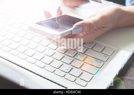 Frau mit Mobiltelefon und Laptop auf ihrem Schreibtisch, Online Shopping und Marketing Konzept Stockfoto