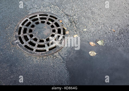 Runde Abwasserkanal Kanaldeckel in Asphalt Straße, Bürgersteig, Ansicht von oben Stockfoto