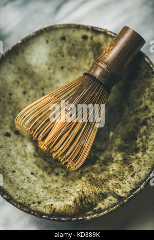 Flachbild-lay der japanischen Werkzeuge für die Zubereitung von Matcha Tee. Matcha Pulver in Blechdose, Chasen Bambusbesen, Chawan Schüssel über grauer Hintergrund, Ansicht von oben Stockfoto