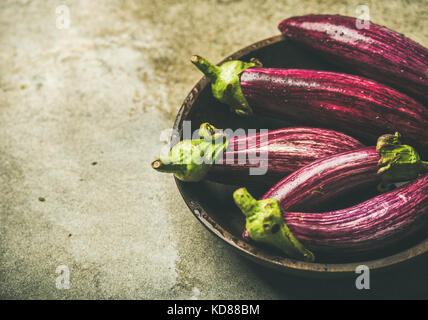 Frische rohe Herbst Ernte lila Auberginen oder Auberginen in Houten über grauer Beton Stein, selektiver Fokus, kopieren. Gesund im Herbst Stockfoto