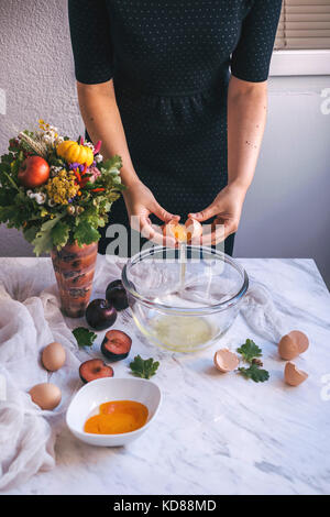 Frau Eier trennen, Eiweiß und Eigelb in einer Schüssel beim Backen eines Kuchens Stockfoto