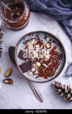 Chia Pudding mit hausgemachte Schokolade haselnuss Verbreitung gekrönt mit Nüssen und Kakao Nibs Stockfoto