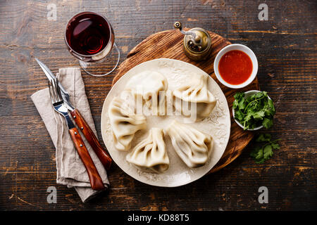 Georgische Knödel Khinkali mit Fleisch und Tomaten würziger Soße auf weiße Platte und Wein Stockfoto