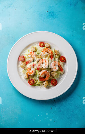 Caesar Salat mit Garnelen und Croutons auf blauem Hintergrund Kopie Raum Stockfoto