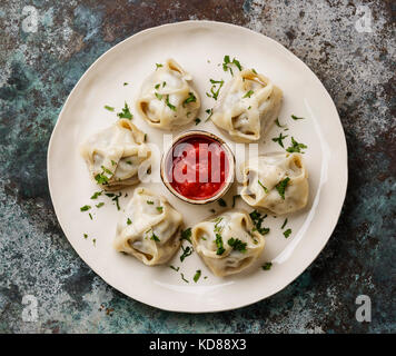 Traditionelle gedämpfte Teigtaschen Manti mit Tomatensauce. Stockfoto