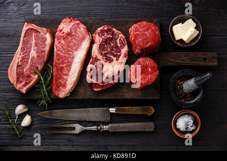 Vielzahl an Raw Black Angus Prime Fleisch steaks Blade auf den Knochen, Roastbeef, Rib Eye, Filet Filet mignon auf Holzbrett und Gewürzen