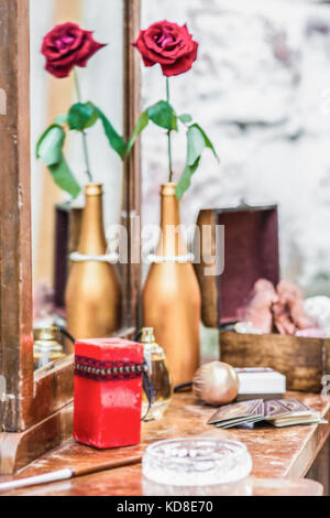 Kerze auf einem Schminktisch und rote Rosen in einer vergoldeten Flasche Stockfoto