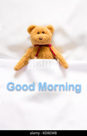 Teddybär in der weißen Bett lag, mit der Meldung 'Guten Morgen' Stockfoto